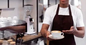 Imagem de um barista segurando uma caneca com a técnica do latte art