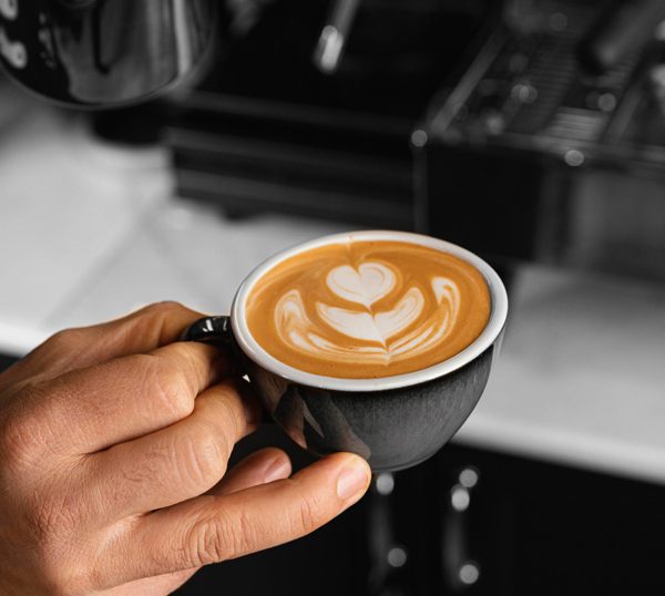 Caneca com latte art em cima no formato de um coração