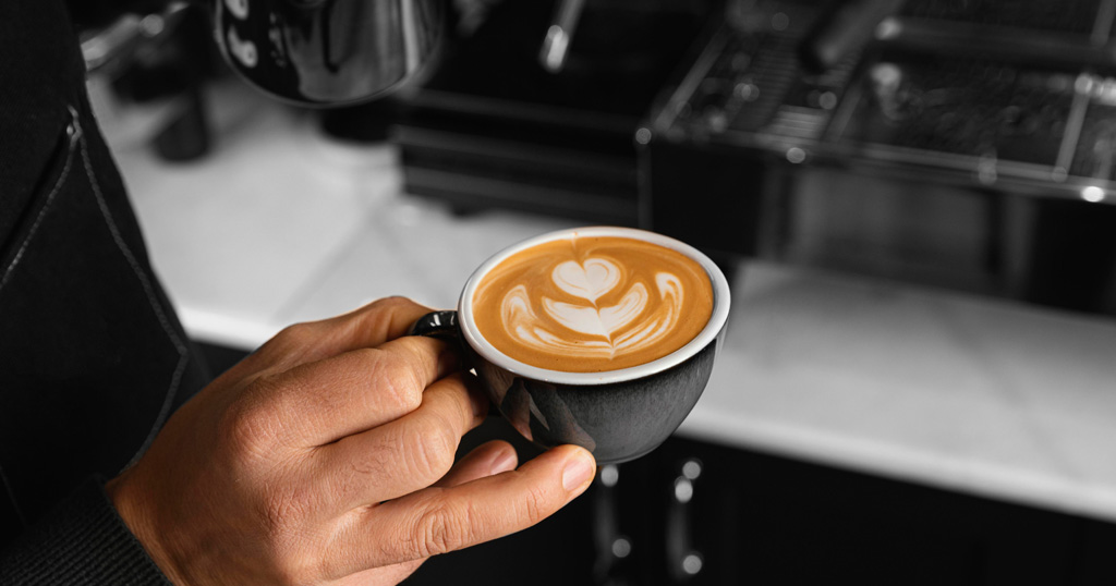 Caneca com latte art em cima no formato de um coração