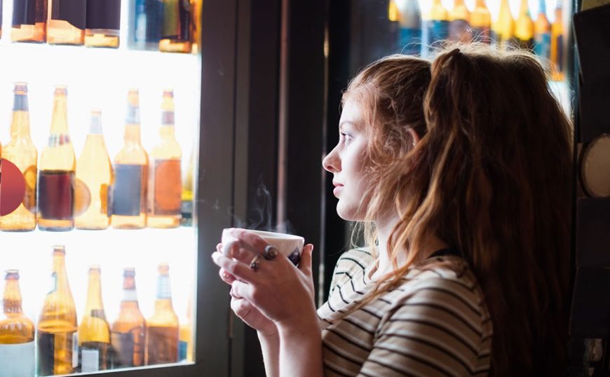 Mulher observando cervejas através da porta de vidro da cervejeira