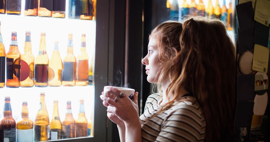 Mulher observando cervejas através da porta de vidro da cervejeira