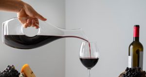 Imagem de um decanter de vinhos preenchendo uma taça de vinhos